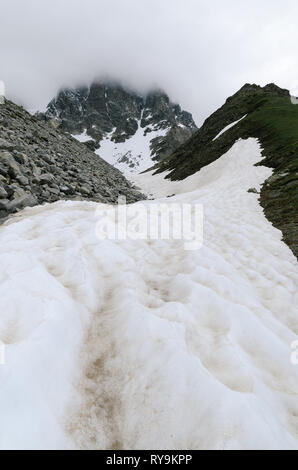 Frühling in den Bergen. Schnee und Moräne auf dem Grat. Trübes Wetter. Landschaft unter dem Gipfel Ushba. Zemo Swanetien, Georgien, Kaukasus Stockfoto