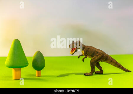 Spielzeug Dinosaurier in einem Spielzeug Wald. wie ein echter Dino auf einem hellen Studio Hintergrund mit Holz- Bäume. Eco Spielzeug. Stockfoto