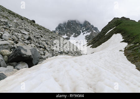 Frühling in den Bergen. Schnee und Moräne auf dem Grat. Trübes Wetter. Landschaft unter dem Gipfel Ushba. Zemo Swanetien, Georgien, Kaukasus Stockfoto