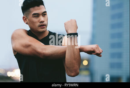 Passen junge Mann, muskulös, außerhalb stretching Hände und weg schauen. Asiatische fitness Modell tun warmup Workout. Stockfoto