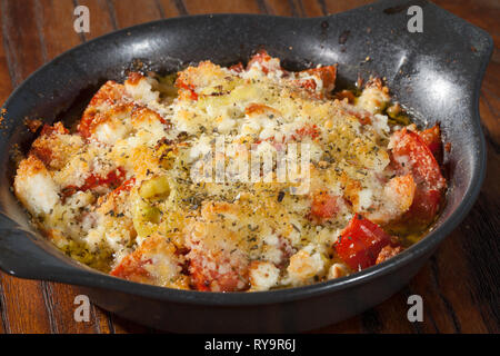 Omelette mit Schinken, Käse Tomaten Pfeffer in schwarzem Ton Schüssel auf hölzernen Tisch serviert. Stockfoto