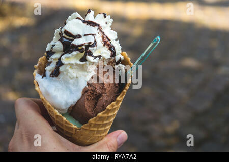 Icecream in drei Geschmacksrichtungen, Schlagsahne und Schokoladensauce in einer Waffel Stockfoto
