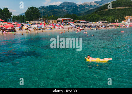 Junger Erwachsener Mann Schwimmen auf Gelb aufblasbare Matratze im blauen Meer. Stockfoto