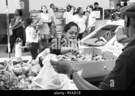 Port of Spain, Trinidad und Tobago - November 28, 2015: alte Frau kauft Gemüse oder Obst im Freien auf lokalen Süden Markt am Straßenbild Hintergrund Stockfoto