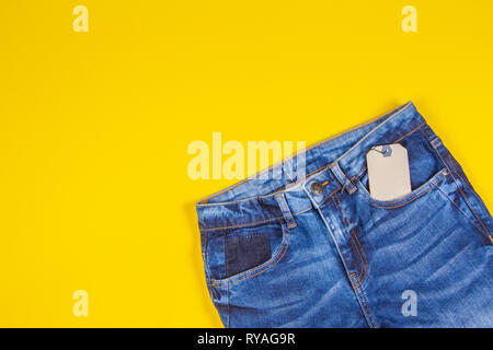 Leeres Etikett Preisschild beschriften mit Blue Jeans auf gelbem Hintergrund Stockfoto