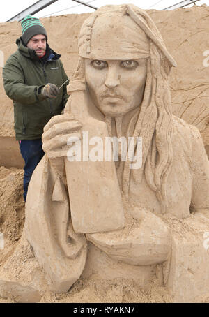 Binz, Deutschland. 12 Mär, 2019. Der Bildhauer Bagrat Stepanayan aus Russland arbeitet auf dem Sand Skulptur Johnny Depp als Captain Jack Sparrow in einer Szene des Films "Fluch der Karibik" auf dem Gelände der Sandskulpturenfestival. Künstlerinnen und Künstler aus verschiedenen europäischen Ländern werden derzeit erstellen 45 riesige Zahlen für die 10 Sand Skulptur zeigen im Ostseebad Binz. Der Sand Skulpturen zeigen, eröffnet am 16.03.2018. Quelle: Stefan Sauer/dpa-Zentralbild/dpa/Alamy leben Nachrichten Stockfoto