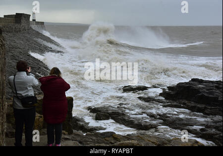 Porthcawl, in Bridgend, Südwales. 13. Mär 2019. UK Wetter: Eine gelbe Wetter Warnung bleibt für viel von Großbritannien heute als Sturm Gareth sich quer durch das Land. Sturm Gareths starke Stürme und Starkregen haben, wodurch Unterbrechungen, mit Schiene und Straße links. Bilder zeigen die Szene in Porthcawl, in Bridgend, Südwales, heute Morgen. Mit dem Leuchtturm von riesigen Wellen von Sturm Gareth getroffen. Fotografen sind abgebildet, die auf Felsen thront als Wellen kommen an Land abstürzt. Stockfoto