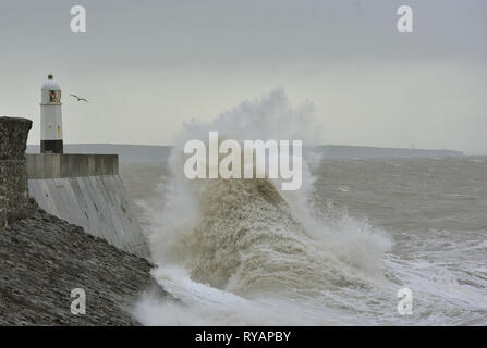 Porthcawl, in Bridgend, Südwales. 13. Mär 2019. UK Wetter: Eine gelbe Wetter Warnung bleibt für viel von Großbritannien heute als Sturm Gareth sich quer durch das Land. Sturm Gareths starke Stürme und Starkregen haben, wodurch Unterbrechungen, mit Schiene und Straße links. Bilder zeigen die Szene in Porthcawl, in Bridgend, Südwales, heute Morgen. Mit dem Leuchtturm von riesigen Wellen von Sturm Gareth getroffen. Fotografen sind abgebildet, die auf Felsen thront als Wellen kommen an Land abstürzt. Stockfoto