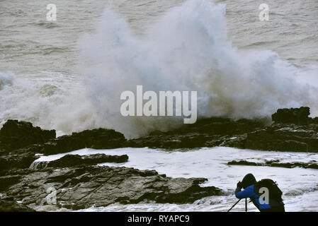 Porthcawl, in Bridgend, Südwales. 13. Mär 2019. UK Wetter: Eine gelbe Wetter Warnung bleibt für viel von Großbritannien heute als Sturm Gareth sich quer durch das Land. Sturm Gareths starke Stürme und Starkregen haben, wodurch Unterbrechungen, mit Schiene und Straße links. Bilder zeigen die Szene in Porthcawl, in Bridgend, Südwales, heute Morgen. Mit dem Leuchtturm von riesigen Wellen von Sturm Gareth getroffen. Fotografen sind abgebildet, die auf Felsen thront als Wellen kommen an Land abstürzt. Stockfoto