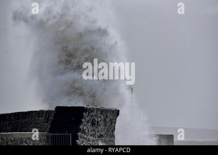 Porthcawl, in Bridgend, Südwales. 13. Mär 2019. UK Wetter: Eine gelbe Wetter Warnung bleibt für viel von Großbritannien heute als Sturm Gareth sich quer durch das Land. Sturm Gareths starke Stürme und Starkregen haben, wodurch Unterbrechungen, mit Schiene und Straße links. Bilder zeigen die Szene in Porthcawl, in Bridgend, Südwales, heute Morgen. Mit dem Leuchtturm von riesigen Wellen von Sturm Gareth getroffen. Fotografen sind abgebildet, die auf Felsen thront als Wellen kommen an Land abstürzt. Stockfoto