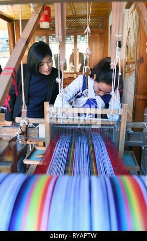 Peking, der chinesischen Provinz Yunnan. 13 Feb, 2019. Ventilator Yongzhen (L), ein Abgeordneter der 13. Nationalen Volkskongress (NVK), führt eine Forschung auf Textil Weberei Fähigkeiten der Naxi ethnische Gruppe in Lijiang Altstadt, im Südwesten der chinesischen Provinz Yunnan, 13.02.2019. Credit: Yang Zongyou/Xinhua/Alamy leben Nachrichten Stockfoto