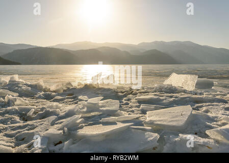 Wunderschöne Aussicht auf gefrorenem See Teletskoye mit Eis, Schollen und die Sonne über die Berge an einem sonnigen Morgen Stockfoto