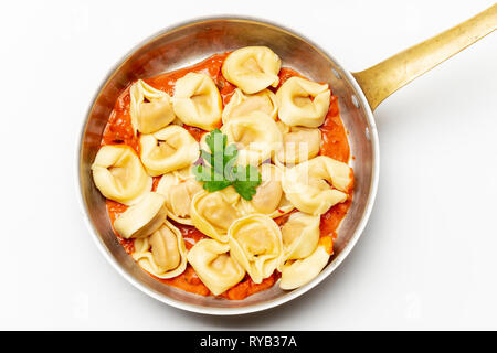 Tortellini auf Weiß mit Tomatensauce. Stockfoto