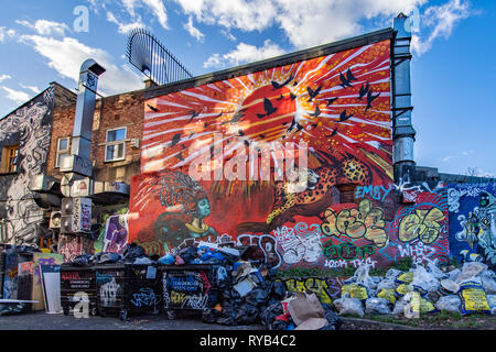 Graffiti an der Wand und Mülltonnen und Taschen. Pedley Street, in der Nähe der Brick Lane, London. Stockfoto
