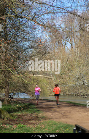 Zwei Läuferinnen auf schotterweg Lazenbee der Boden am Fluss Cherwell Oxford University Parks in der Sonne im Winter/Frühjahr Stockfoto