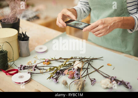 Nahaufnahme des unkenntlich Frau unter Mobile Photo von Blume Zusammensetzung in art studio, Kopie Raum Stockfoto