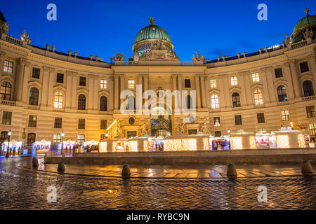 Die Hofburg, die Hofburg der Habsburger, von Michaelerplatz mit einem Weihnachtsmarkt, in der Dämmerung, Wien, Österreich. Stockfoto