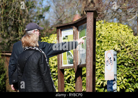 Touristen oder Einheimische schauen und zeigen auf Karte von der Universität Oxford Parks und Vorstand an einem sonnigen Tag im Winter/Frühjahr beachten Stockfoto