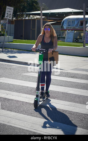 Frau Reiten eines elektrischen E Scooter zu mieten, South Congress Avenue, Austin, Texas, USA Stockfoto