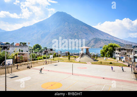 Santiago Atitlan See, Lake Atitlan, Guatemala - 8. März, 2019: Kids im Lakeside Basketball spielen mit Vulkan San Pedro hinter in der grossen Stadt am See Stockfoto