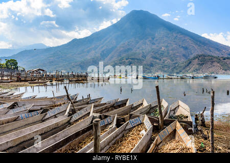 Santiago Atitlan See, Lake Atitlan, Guatemala - 8. März, 2019: Reihen von Lakeside traditioneller Kanus mit Vulkan San Pedro hinter in der größten Stadt am See Stockfoto