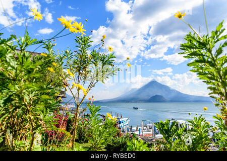 Panajachel, Atitlan See, Guatemala - 8. März 2019: Blumen frame Blick auf die Boote, den See und Toliman & Atitlan Vulkane in Panajachel am Atitlán-See Stockfoto