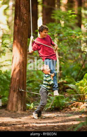 Zwei Jungen Balancieren auf das Seil im Wald. Stockfoto