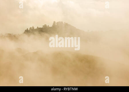 Am frühen Morgen Sonne wirft Orange glühen auf Nebel über Berggipfel Stockfoto