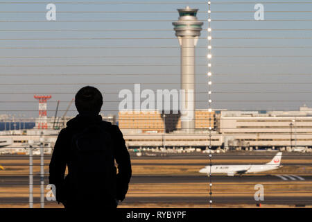 Ein Mann beobachtet, wie Verkehrsflugzeuge auf der Aussichtsplattform des Haneda International Airport, Tokio, Japan, starten und landen. Stockfoto