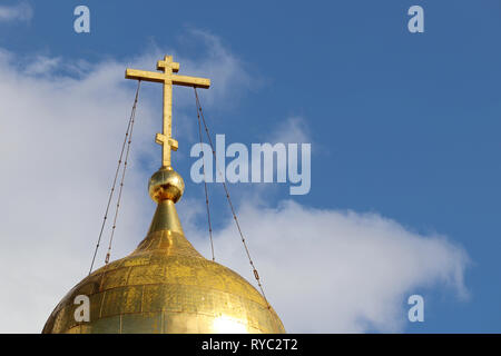 Goldene Kuppel der Orthodoxen Kirche mit dem Kreuz gegen den blauen Himmel mit weißen Wolken. Christlichen Tempel, Hintergrund für religiöse Grußkarte Stockfoto