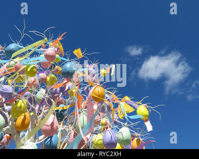 Ostern Eier gegen den blauen Himmel mit weißen Wolken. Festliche Baum mit Ostern Dekorationen und bunten Bändern, Hintergrund für die Grußkarte Stockfoto