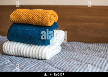Stapel der gemütliche gestrickte Pullover auf dem Bett. Stockfoto