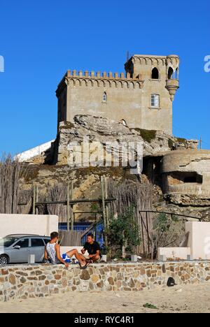 Blick auf St. Catherines Burg (Castillo Santa Catalina) mit zwei Männer an einer Wand im Vordergrund, Tarifa, Spanien sitzen. Stockfoto