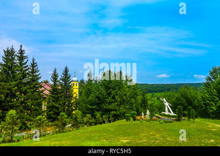 Bursuc Hancu Kloster Landschaft, Blick auf den Garten und den Wald mit einem Denkmal des Gottes Jesus Christus mit dem Kreuz auf dem Rücken Stockfoto