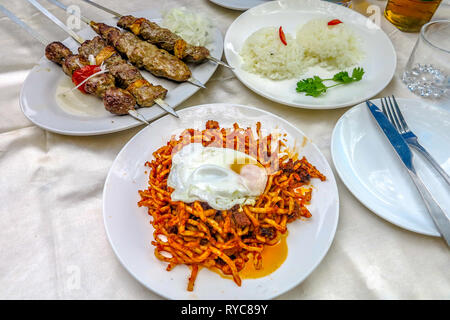 Usbekische traditionelle Lamm am Spieß mit Reis und Nudeln gebraten Würzige Lagman Gericht mit pochierten Eiern Stockfoto