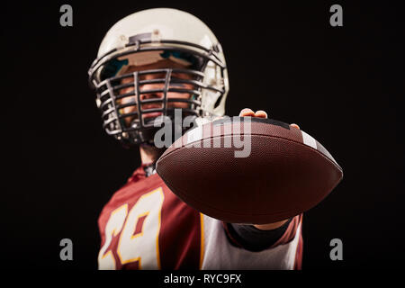 Portrait von American Football Spieler mit Ball im Vordergrund. Stockfoto