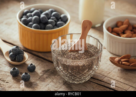 Frische Heidelbeeren, Mandel- und Chia Samen mit Milch auf Holzbrett. Ideal gesundes Frühstück Konzept. Stockfoto