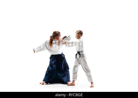 Mann und jugendlich Junge Kämpfe an Aikido Training in Martial Arts School. Gesunder Lebensstil und Sport Konzept. Fightrers in weißen Kimono auf weißem Hintergrund. Karate Männer mit konzentrierten Gesichter in Uniform. Stockfoto