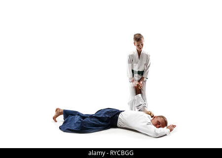 Mann und jugendlich Junge Kämpfe an Aikido Training in Martial Arts School. Gesunder Lebensstil und Sport Konzept. Fightrers in weißen Kimono auf weißem Hintergrund. Karate Männer mit konzentrierten Gesichter in Uniform. Stockfoto