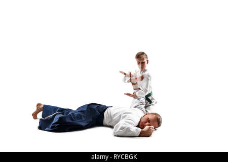 Mann und jugendlich Junge Kämpfe an Aikido Training in Martial Arts School. Gesunder Lebensstil und Sport Konzept. Fightrers in weißen Kimono auf weißem Hintergrund. Karate Männer mit konzentrierten Gesichter in Uniform. Stockfoto