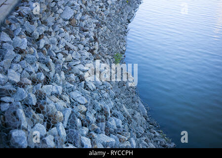 Felsen von Stahl net gesichert werden, um die Sicher ohne Rutschen ins Wasser Teich Stockfoto