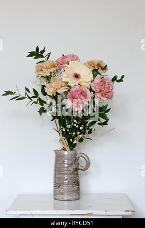 Schönen Blumenstrauß aus Nelken, Chrysanthemen und in einer Keramik Vase auf einem neutralen Hintergrund Stockfoto