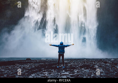 Eine Person admirnig die Schönheit der Skogafoss Wasserfall in Island entfernt Stockfoto