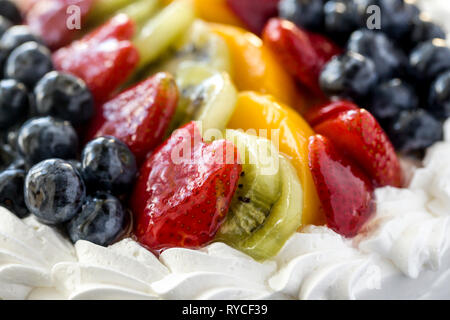 Ein Sortiment von Glasierten Früchten wie bluerberries, Erdbeeren und Kiwis, auf einem Kuchen. Stockfoto