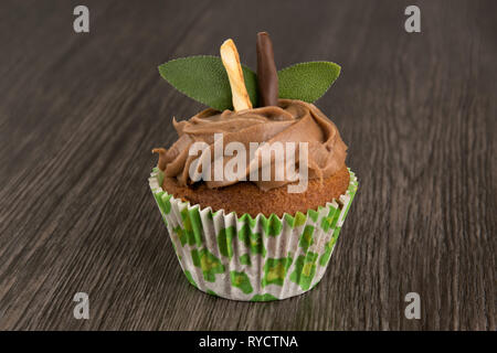 Isolierte chocolate Cupcake auf dunklen Holztisch Hintergrund mit Minze. Gebäck muffin Stockfoto