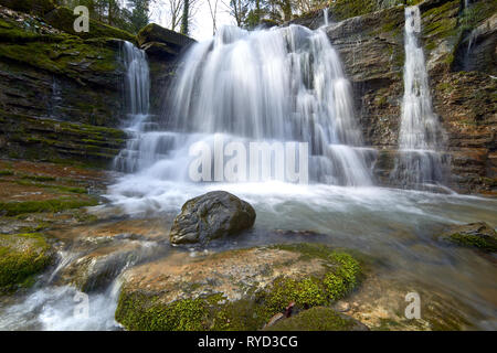 Wasserfall an einem Gebirgsfluss mit Moos bedeckt Felsbrocken Stockfoto