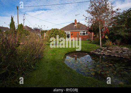 Städtische Garten mit Teich, Rasen, Bäume und Bungalow Ringwood Hampshire England Großbritannien Oktober 2016 Stockfoto