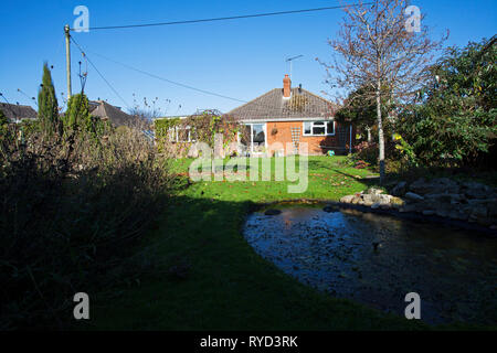 Städtische Garten mit Teich, Rasen, Bäume und Bungalow Ringwood Hampshire England UK November 2016 Stockfoto