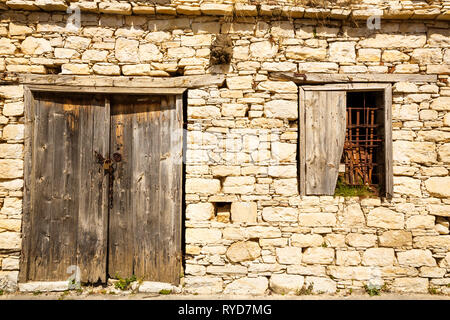 Alte Holztür mit Kette und Fenster in Limnatis Dorf, Zypern. Stockfoto
