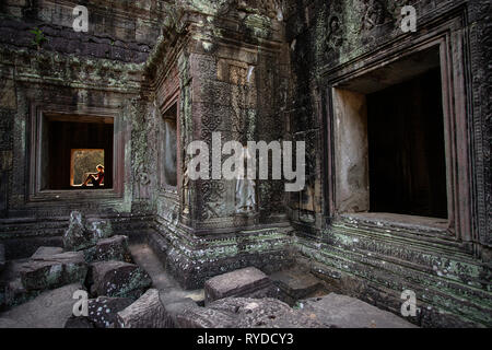 Frau sitzt auf dem Fenster in alten und majestätischen Tempel von Preah Khan bei Sonnenuntergang. Großer Kreis von Angkor, Siem Reap, Kambodscha Stockfoto